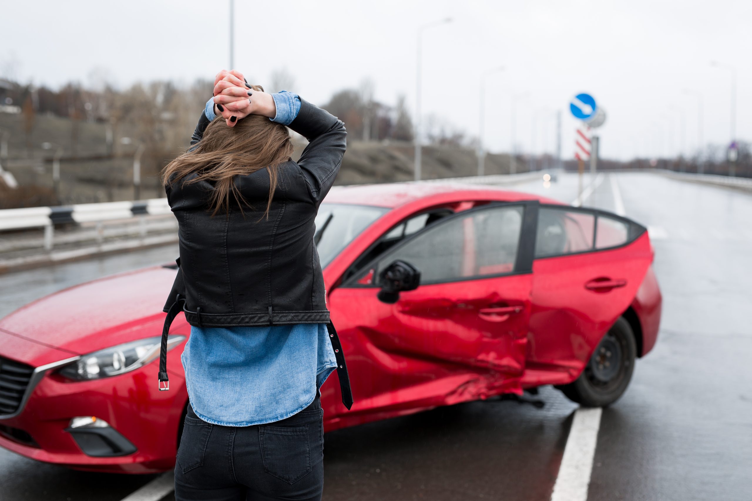 Woman stands near a broken car after an accident. call for help. car insurance.