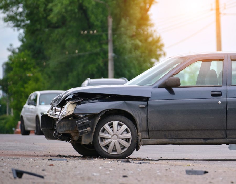 Damaged in car accident vehicle on city street crash site.